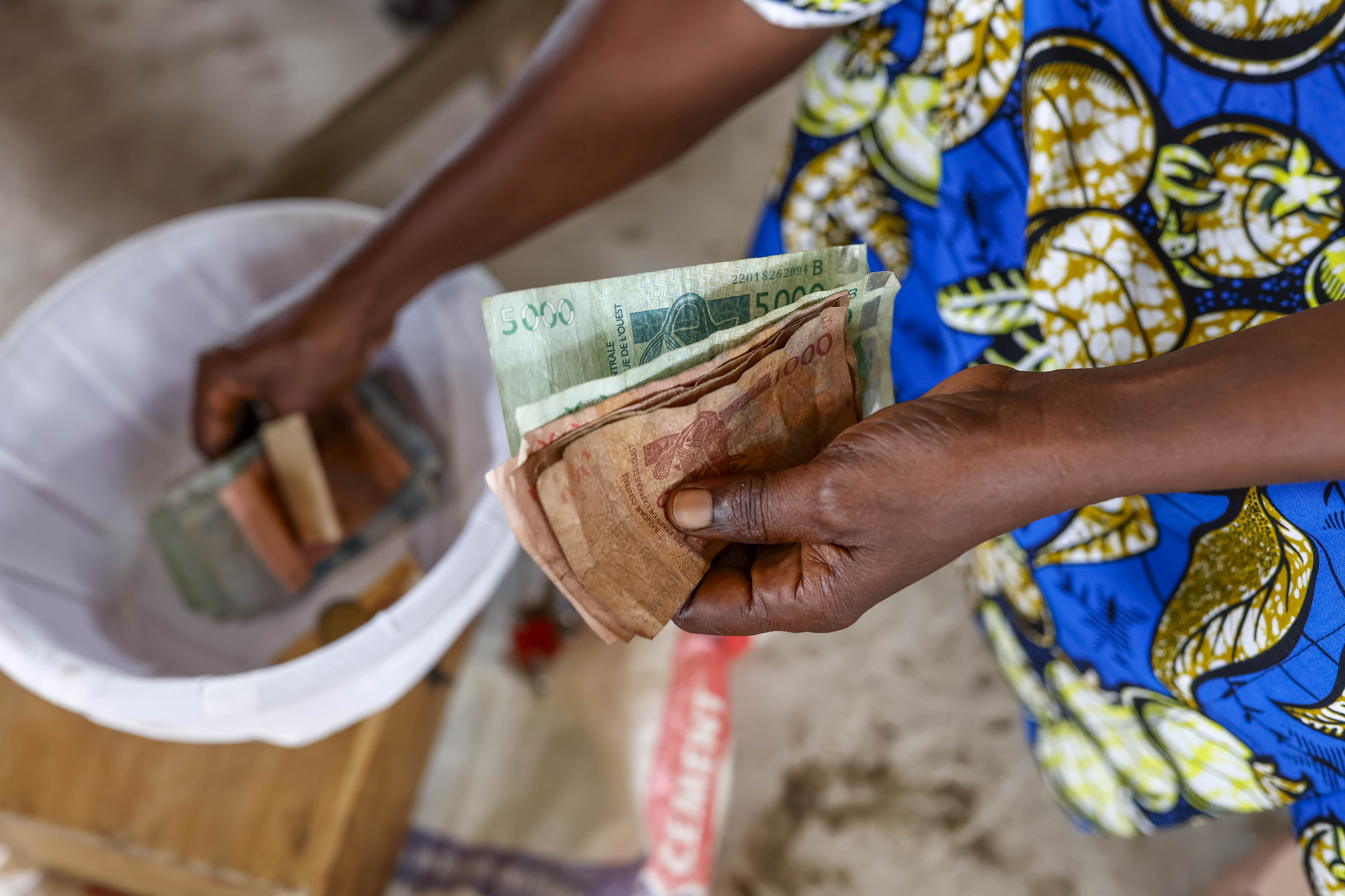 someone paying for their microfinance loan in cash, reflecting the focus of this podcast on the topic of microcredit