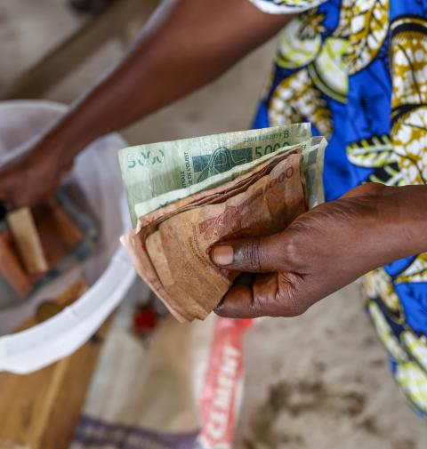 someone paying for their microfinance loan in cash, reflecting the focus of this podcast on the topic of microcredit